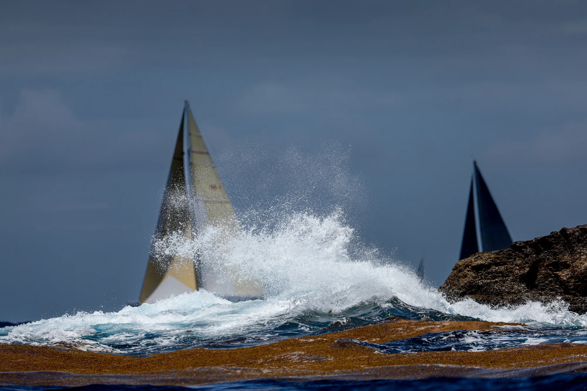 Sailboats beyond breaking waves. Photograph by Paul Wyeth